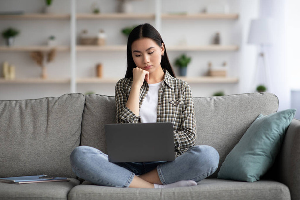 Pensativo asiático señora usando laptop, buscando trabajo en línea - Foto, Imagen