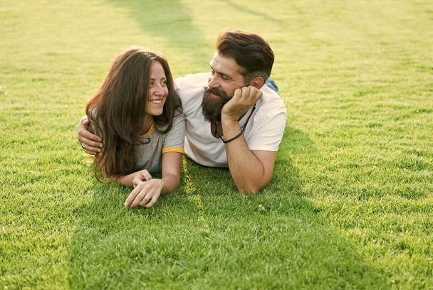 Carefree couple enjoying sunny day relaxing on green meadow, romantic date concept - Photo, Image