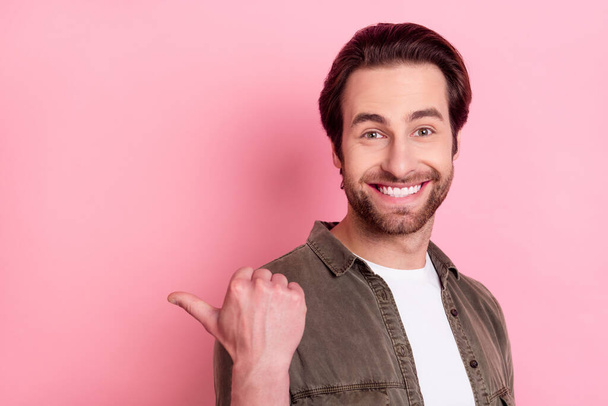 Photo of impressed pretty young guy dressed brown shirt pointing thumb empty space isolated pink color background - Φωτογραφία, εικόνα