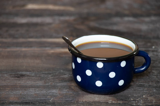 taza azul con guisantes blancos en una mesa de madera vieja, una taza con café por la mañana - Foto, imagen