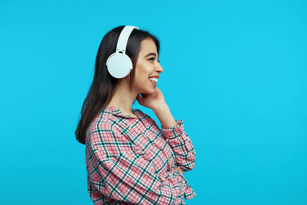 Profil des Mädchens trägt weiße Kopfhörer hört fröhlich Musik und lächelt - Foto, Bild