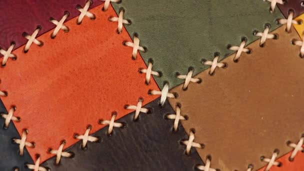 multicolored patchwork leather surface with large stitching turns around, close-up view - Footage, Video