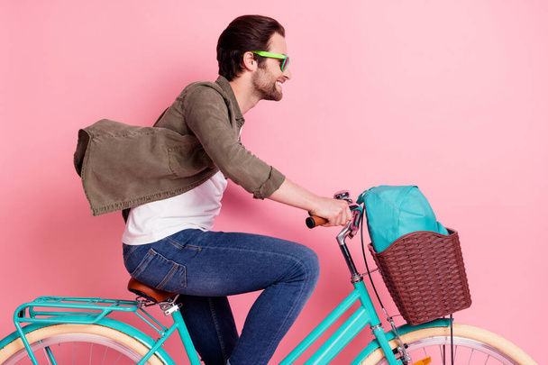Profile side photo of young guy happy positive smile ride bicycle trip fast look empty space isolated over pastel color background - Foto, Bild