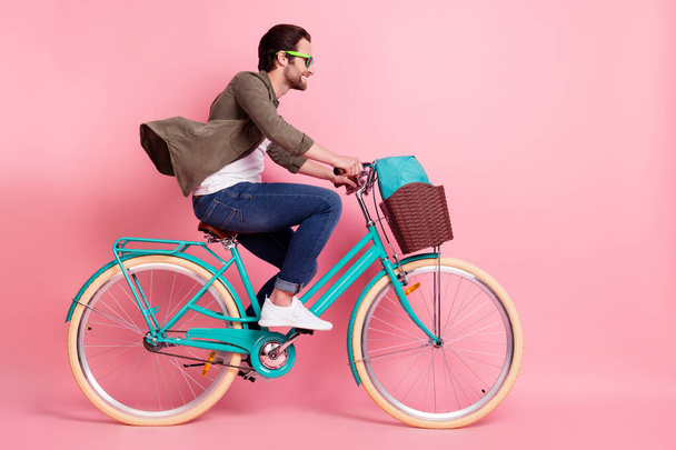 Full length body size profile side view of attractive cheerful guy riding bike isolated over pink pastel color background - Foto, Bild