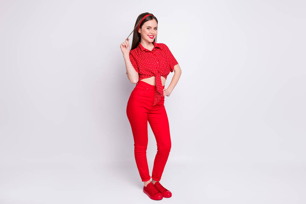 Photo of playful flirty girl play curl look camera wear red dotted blouse trousers footwear isolated grey color background - Foto, imagen