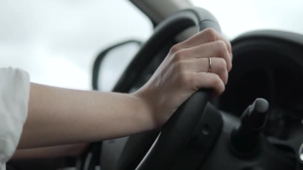 Een close-up van de handen op het stuur, een vrouw rijdt in een auto - Video