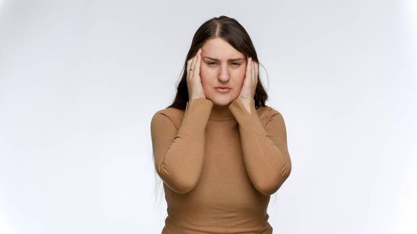 Mujer joven estresada que sufre de dolor de cabeza frotándose las sienes con las manos. - Foto, Imagen