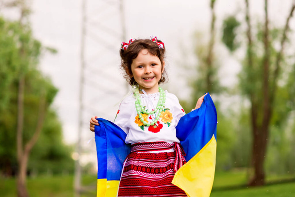 Happy girl with the flag of Ukraine. The girl is dressed in an embroidered shirt - the Ukrainian national dress. August 24 - Independence Day of Ukraine. postcard with patriotic symbols - Fotografie, Obrázek