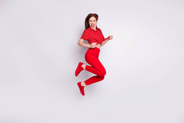 Full length photo of crazy lady jump excited open mouth wear red dotted blouse trousers footwear isolated grey color background - Photo, Image