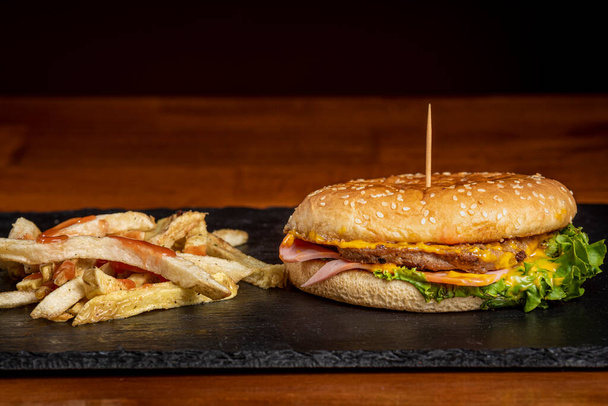 Pyszny i soczysty hamburger z frytkami na drewnianym stole - Zdjęcie, obraz