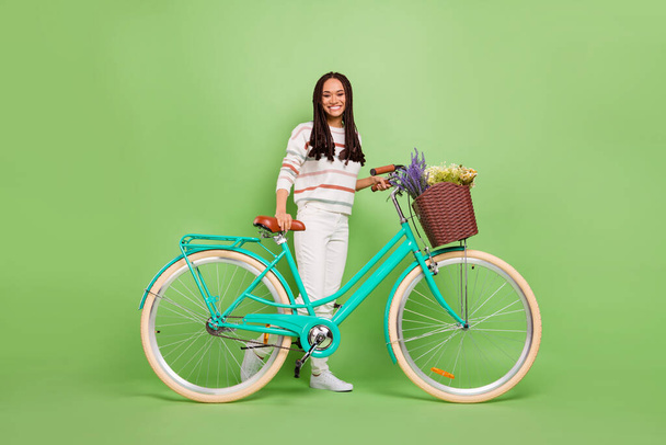 Full length photo of young afro girl happy positive smile ride bicycle trip isolated over green color background - Foto, imagen