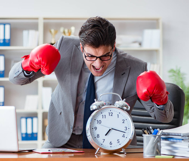Сердитий бізнесмен з боксерськими рукавичками в концепції управління часом
 - Фото, зображення