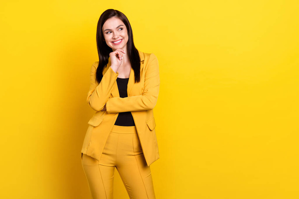 Photo of young pretty woman happy positive smile hand touch chin dream look empty space isolated over yellow color background - Valokuva, kuva