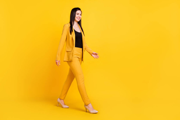 Foto de perfil de tamaño completo de la señora del trabajo joven agradable ir a usar pantalones de chaqueta amarilla aislados en el fondo de color vivo - Foto, imagen