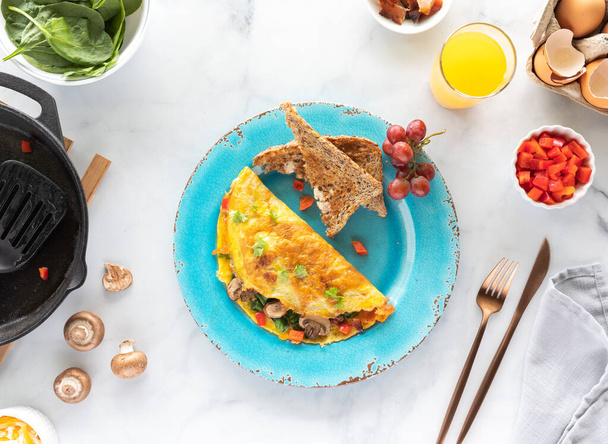 Pohled shora dolů na talíř s čerstvě vyrobenou omeletou podávanou s toastem a pomerančovým džusem. - Fotografie, Obrázek