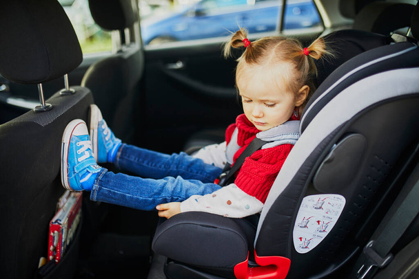 Adorable toddler girl in modern car seat. Little kid traveling by car. Child safety on the road. Trip with an infant - Fotografie, Obrázek