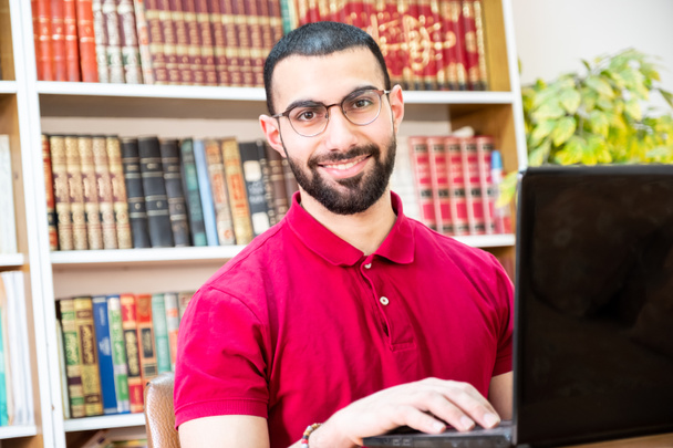 Konferanslarda veya toplantılarda online kanallar aracılığıyla eğitim ve öğretim için dizüstü bilgisayar kullanan Arap bir adam - Fotoğraf, Görsel