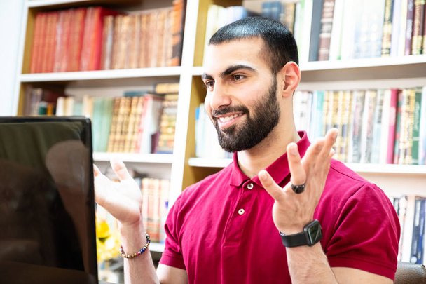 Konferanslarda veya toplantılarda online kanallar aracılığıyla eğitim ve öğretim için dizüstü bilgisayar kullanan Arap bir adam - Fotoğraf, Görsel