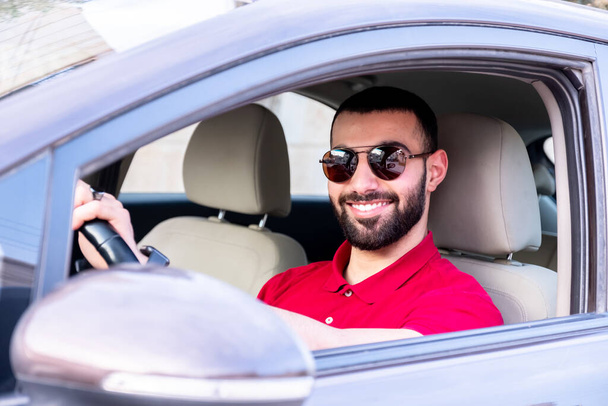 Arabische man rijdt zijn auto met een glimlach en zelfvertrouwen - Foto, afbeelding
