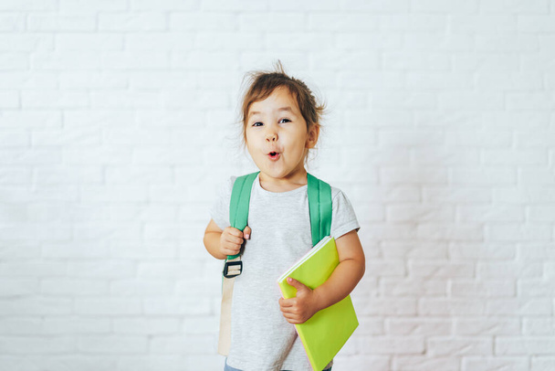 Überraschtes Kind mit Schulsachen vor weißem Hintergrund. - Foto, Bild