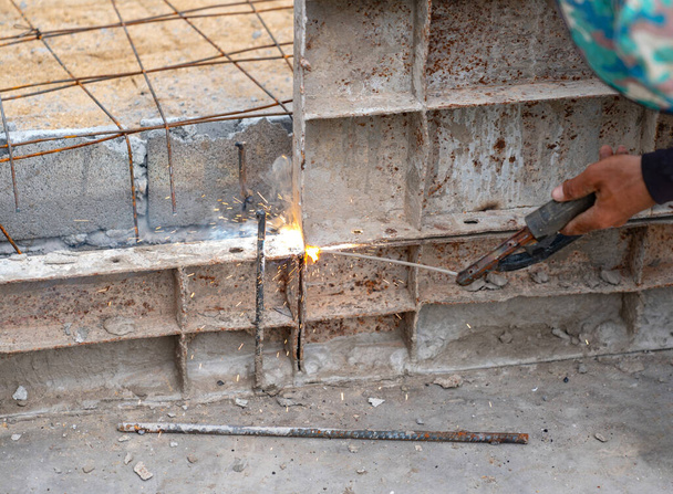 コンクリート用の金属加工を溶接する労働者は、建設現場でそれを注ぎます. - 写真・画像