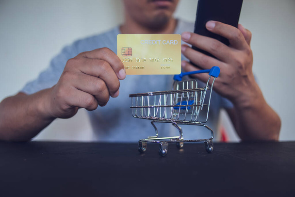 Hombre sosteniendo una tarjeta de crédito y utilizando el teléfono inteligente para el pago en línea, utilizando la aplicación de banca en línea en su teléfono celular. - Foto, imagen