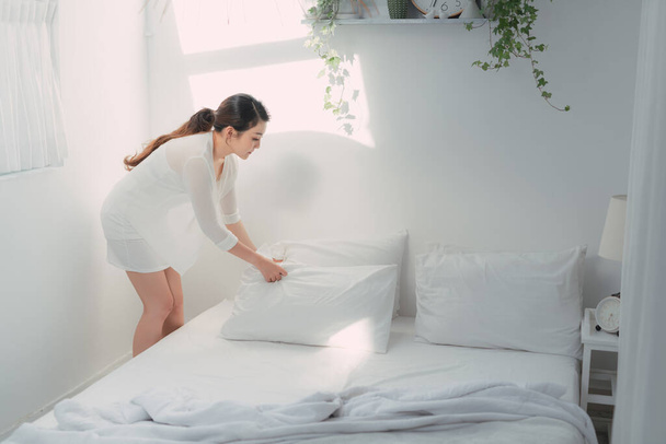 Hacer una cama, chica haciendo su cama en la habitación después de despertar - Foto, Imagen