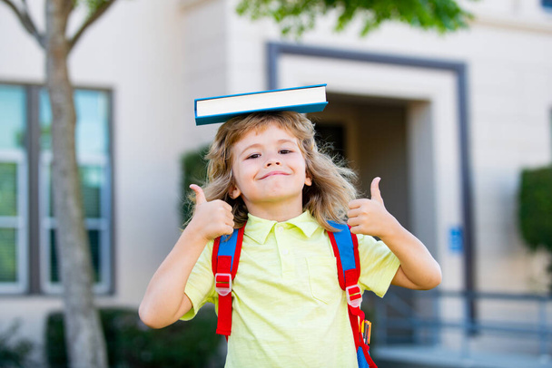 Funny kid ready to school. Schoolboy pupil with backpack outdoor with thumbs up. - Foto, Imagen
