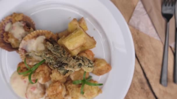Peruánské jídlo: krevety Sauteed s bylinkami a česnekem, dřevěný stůl, podávané na bílém talíři, doprovázené fialovou kukuřičnou šťávou - Záběry, video