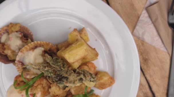 Peruánské jídlo: krevety Sauteed s bylinkami a česnekem, dřevěný stůl, podávané na bílém talíři, doprovázené fialovou kukuřičnou šťávou - Záběry, video