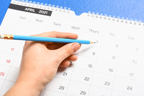 Woman marking date in calendar on color background, closeup - Foto, Bild