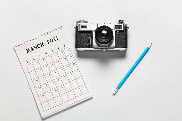 Flip calendario de papel, cámara fotográfica y lápiz sobre fondo claro - Foto, Imagen