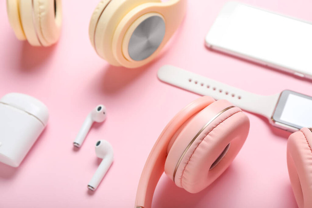 Modern headphones, earphones and smart watch on color background, closeup - Photo, Image