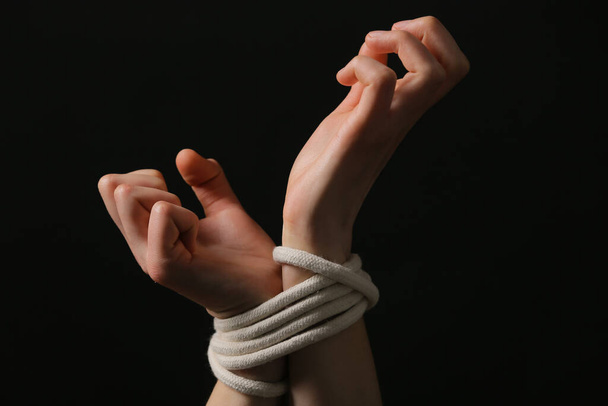Female hostage with tied hands on dark background, closeup - Photo, Image
