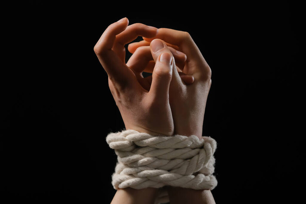 Female hostage with tied hands on dark background, closeup - Foto, afbeelding