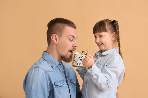 Happy daughter and father with cup of hot cocoa on color background - Fotó, kép