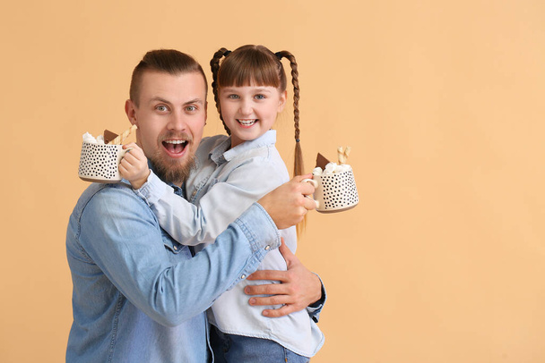 Překvapená dcera a otec s šálky horkého kakaa na barevném pozadí - Fotografie, Obrázek