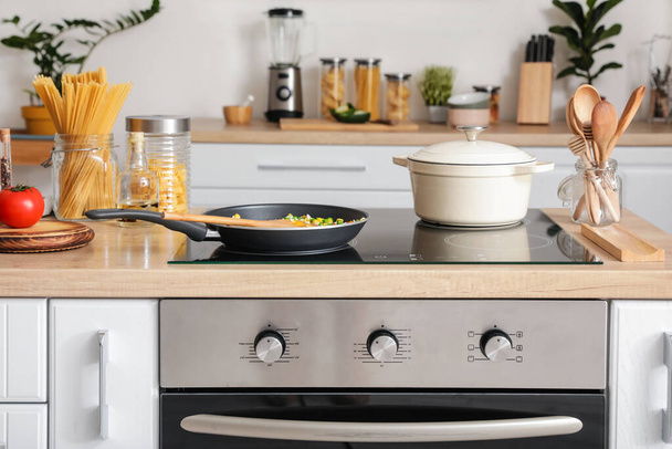 Modern electric stove and utensils in kitchen - Photo, Image