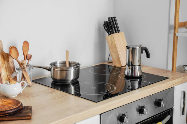 Modern electric stove with cooking pot and coffee maker in kitchen - Photo, Image