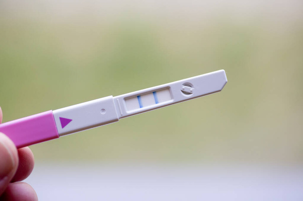 Zwangerschapstest in een vrouwenhand. Medische zwangerschapstest positief. Concept reproductieve gezondheid van vrouwen. - Foto, afbeelding
