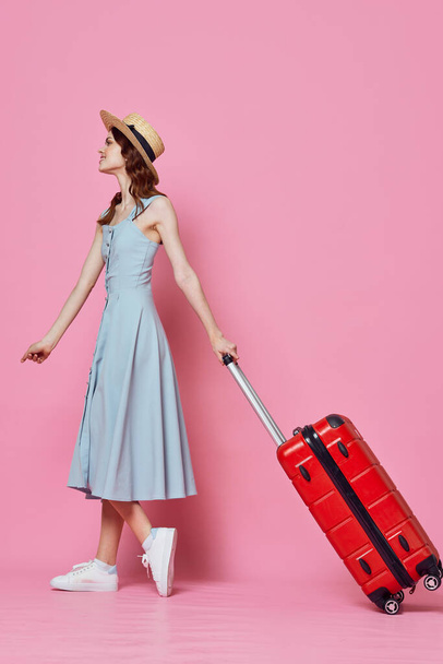 turista mujer en sombrero con maleta roja pasajero estilo de vida rosa fondo - Foto, Imagen