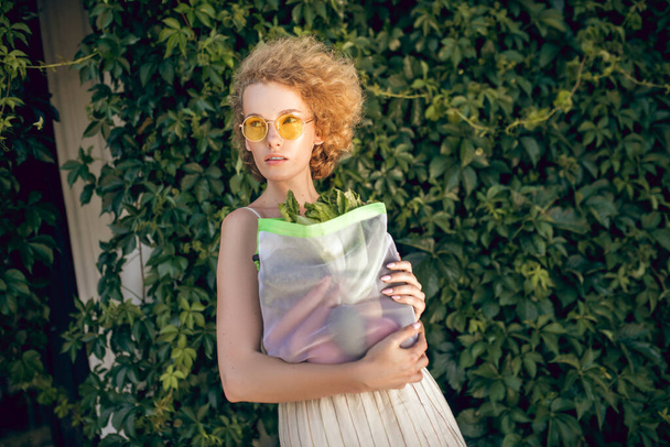 Young woman i holding a bag with vegetables in her hands - Foto, imagen