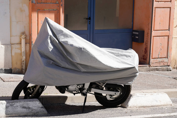 Rua da motocicleta estacionada protegida pelo envoltório protetor prateado que protege a jaqueta de lona da motocicleta da tampa - Foto, Imagem