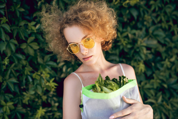 A picture of a young woman with a pack of greens in her hands - Foto, imagen