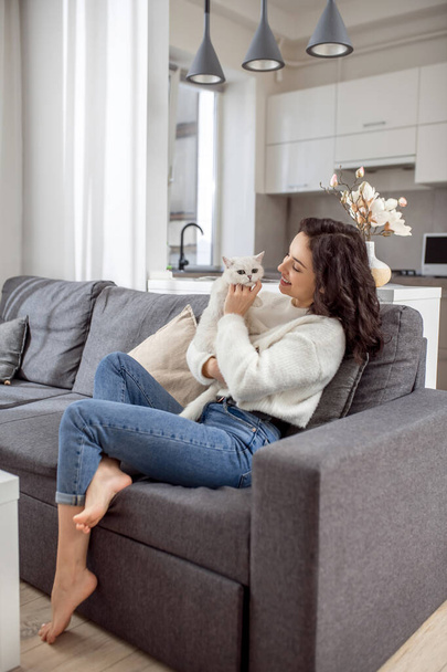 Young woman in white sweater and her cat at home - Foto, Bild