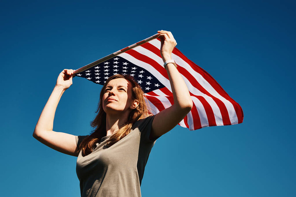 Woman holds usa flag against blue sky - Photo, Image