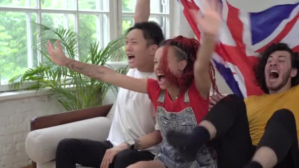 Britse fans kijken thuis naar sport op tv. Gelukkige fans met de vlag van het Verenigd Koninkrijk - Video