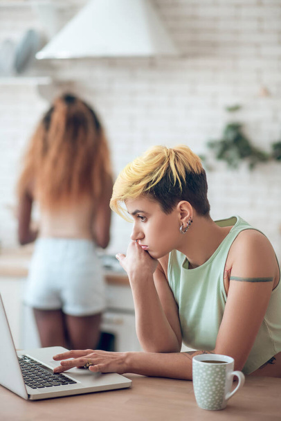 Pensive woman behind laptop and girlfriend at distance - Fotó, kép