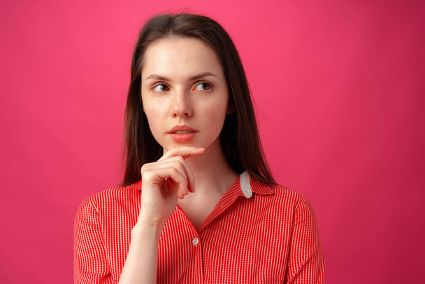Studio portrait of beautiful young woman thinking against pink background - Foto, Imagen