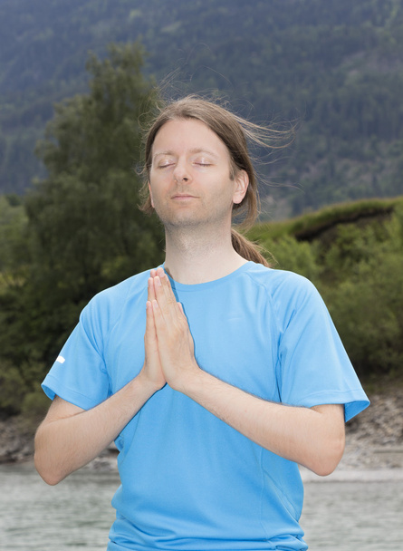 屋外の自然の中でナマステ ポーズ瞑想の若い男 - 写真・画像